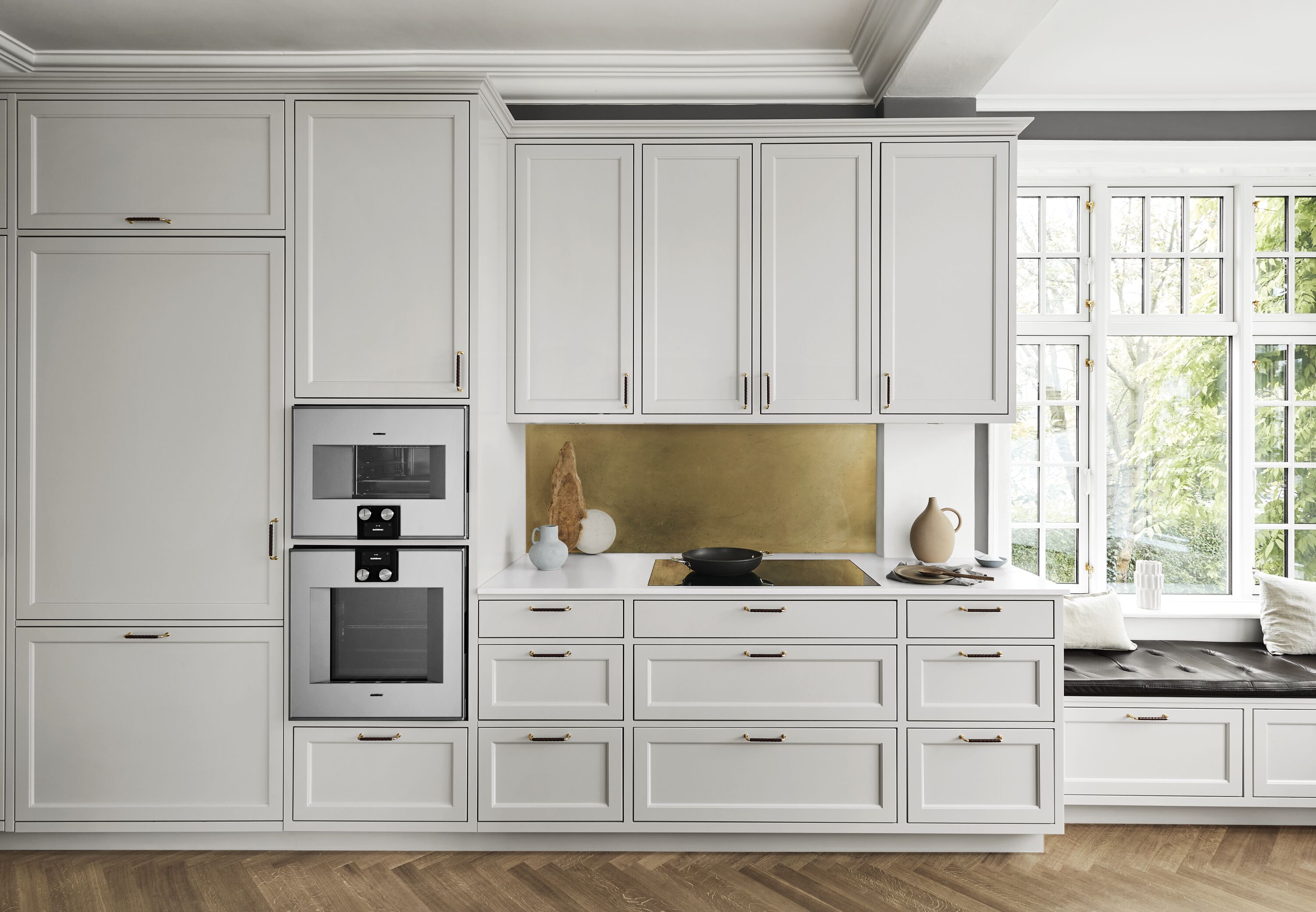 Hvid minimalisk køkken med integreret hvidevarer ogmessing backsplash
